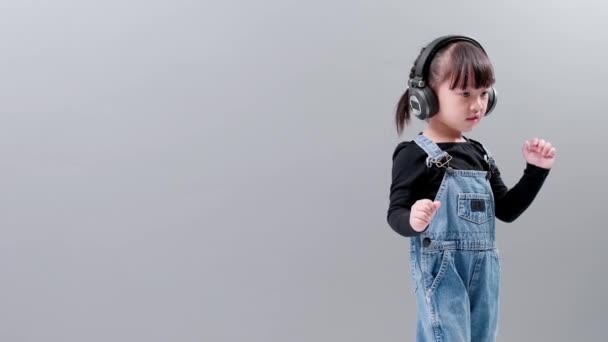 Ребенок Комбинезоне Слушает Музыку Наушниками Танцы Фоне Серого Фона Студии — стоковое видео