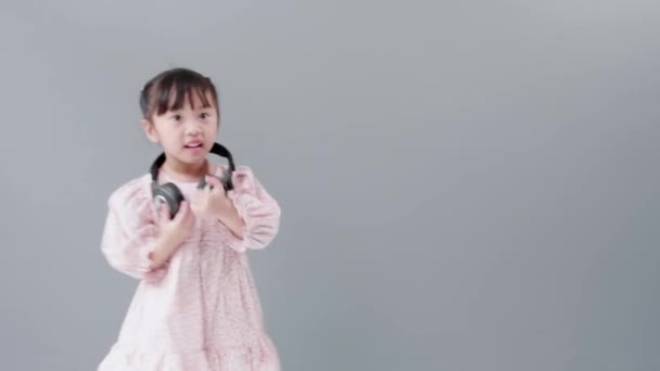 带着耳机的可爱的亚洲女孩喜欢音乐和舞蹈 在工作室里快乐地转身 — 图库视频影像