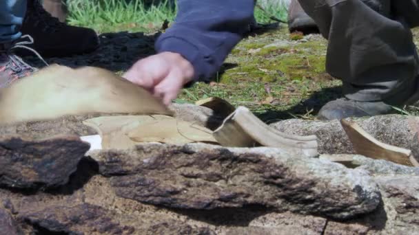 背景に草のある石窯に陶器の小石を置く男の手のクローズアップ — ストック動画