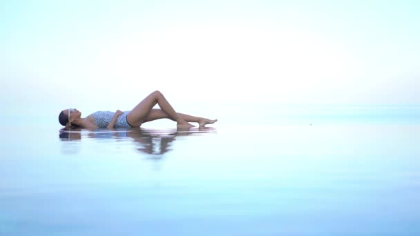 西装革履的离奇女子躺在无边无际的游泳池边与热带海天际线的交汇上 身姿丰满 — 图库视频影像