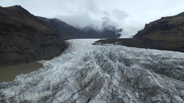 無人機は氷河の凍ったラグーンと尾根を飛んでいます アイスランドの凍ったラグーンと雪に覆われた山脈の景色 — ストック動画