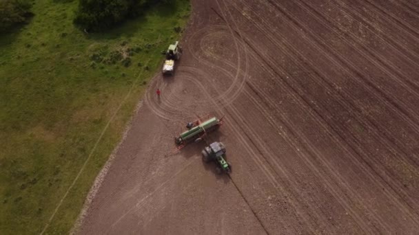 농부들은 농장의 밭에서 트랙터와 쟁기를 수리한다 공중에서 아래로 선회하는 — 비디오