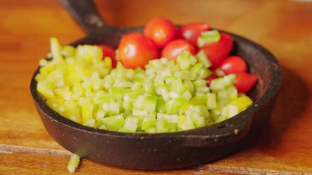 ミニキャスト鉄鍋の手持ち撮影ブルノイズダイスカット緑のカプセシウムとローマトマトのサラダ準備のために — ストック動画