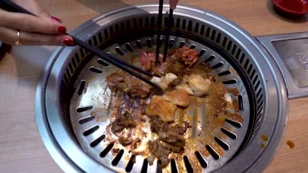 Dory fish and beef is being cooked on hot pan by female chef with red nails