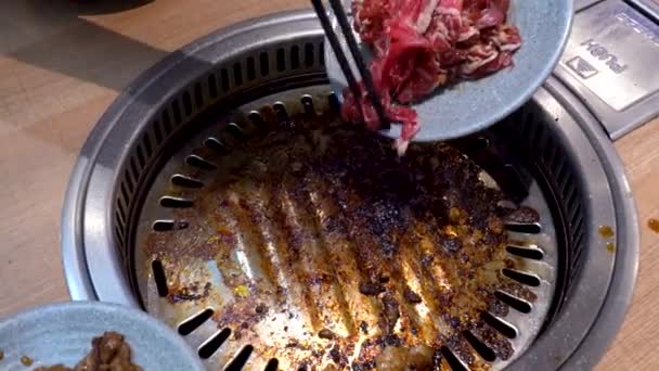 生牛を鍋に入れるために箸を使う料理人 間近で見る — ストック動画