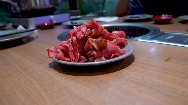 Obrovská hromada syrového hovězího masa v talíři na dřevěném stole před vařením, pohled na pohyb