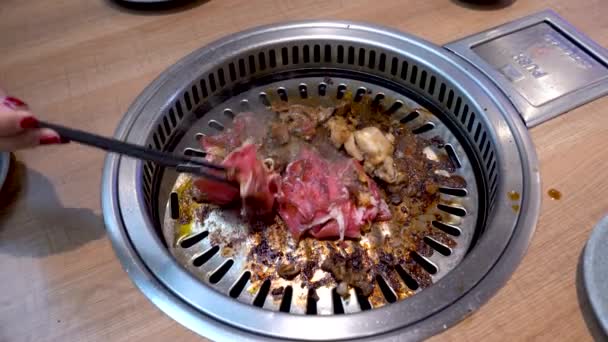 Flipping raw beef in hot pan by female chef with ring and red nails, all you can eat restaurant