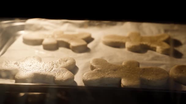Timelapse: Baking man shaped gingerbread cookies in kitchen oven. Cookies rising up. Closeup
