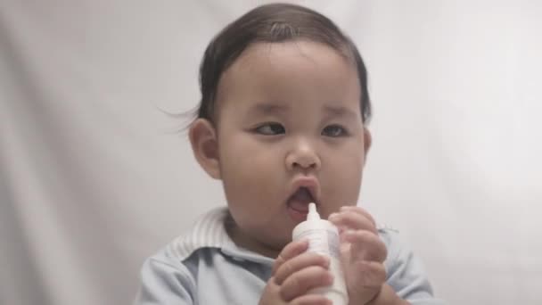 Cute Baby Boy Gnaws Botella Plástico Con Fondo Blanco Cerca — Vídeo de stock