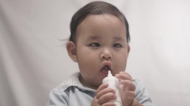 Aranyos kisfiú rágja műanyag palack fehér háttér. - Zárj be