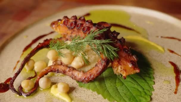 Close up slow motion shot of a complete dish of grilled octopus with chickpeas salad, beautifully garnished and plated with aesthetic cooking concept.