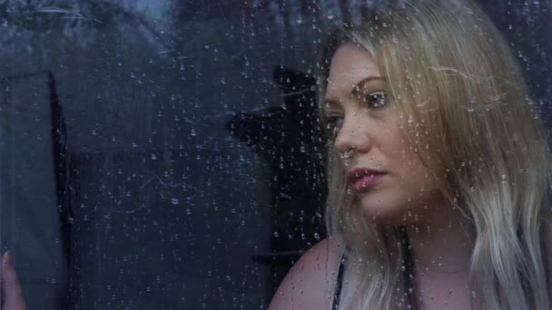 凄凉寂寞的金发女子在雨中看着窗外 — 图库视频影像