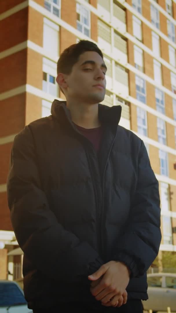 一个年轻人站在一个垂直的住宅区前的画像 — 图库视频影像