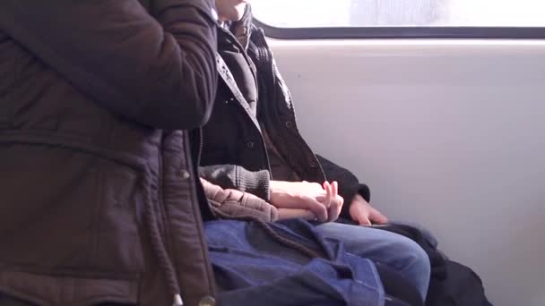 Nő és férfi fogják egymás kezét a vonaton.