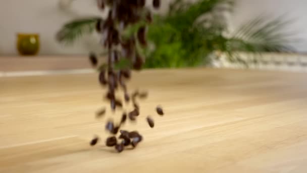Geröstete Kaffeebohnen fallen auf einen Holztisch - Nahaufnahme, statischer Schuss