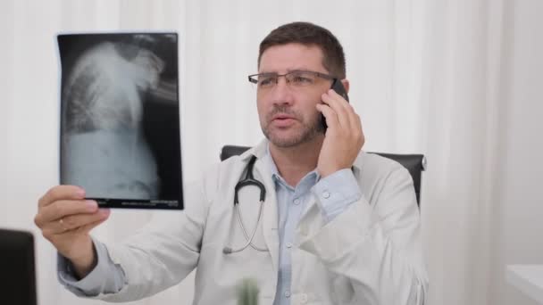 Doktor Röntgen Filmlerine Bakarken Telefonda Konuşuyor Orta Çekim — Stok video