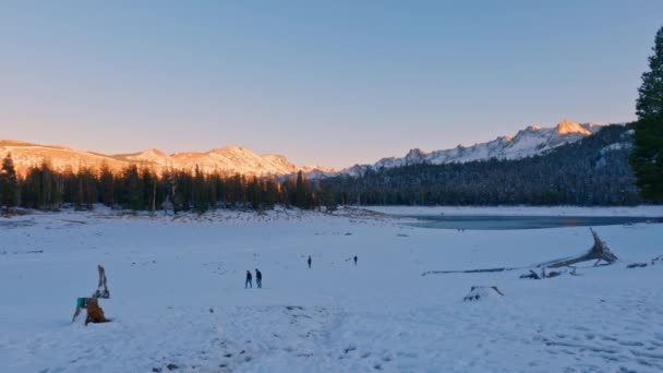 雪象马蹄湖 人们在远处散步 阳光明媚的山和清澈的落日背景 缓慢的泛宁射击 — 图库视频影像
