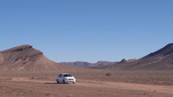 晴れた日の乾燥した風景の中に白い車 手持ち撮影を追跡 — ストック動画
