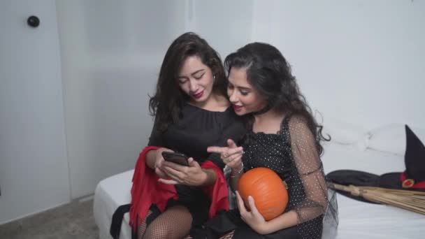 Twee Colombiaanse Vrouwen Zwarte Heksenkostuums Met Pompoen Smartphone Slaapkamer Middelmatig — Stockvideo