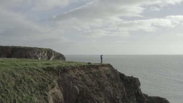 崖の上の無人機パイロットの空中飛行 その先の穏やかな海 — ストック動画