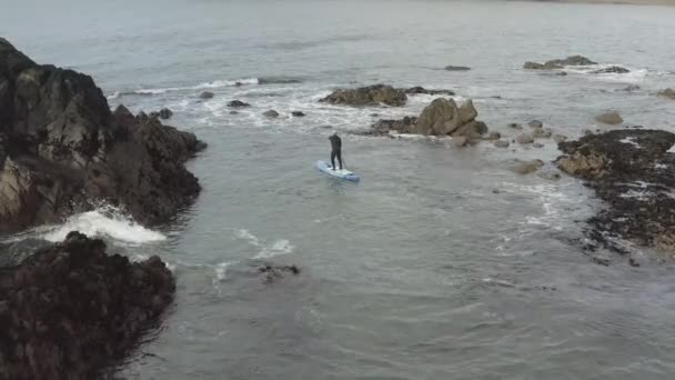 干潮時には海洋島の周りの混沌とした水の上にウェットスーツパドルボーダー — ストック動画