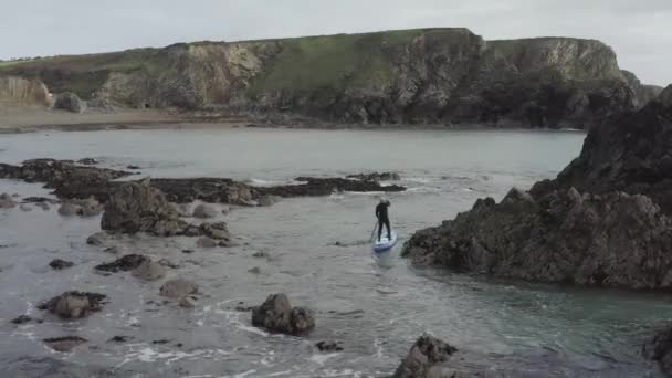 Man Paddlar Sup Paddelbräda Genom Farliga Hav Stenar Nära Stranden — Stockvideo