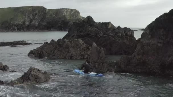 ギザギザの岩の近くの危険な海の混乱の中でウェットスーツのパドルボーダー — ストック動画