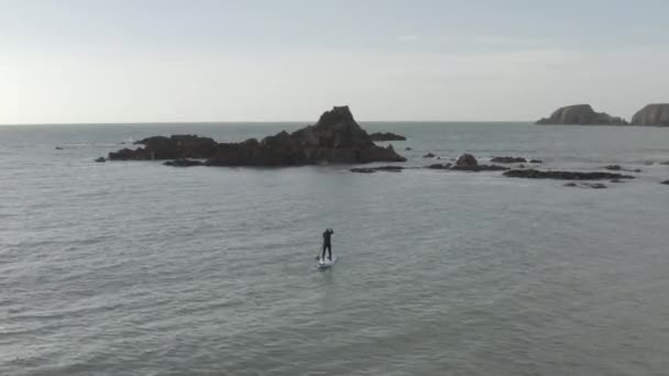 Stand Paddleboarder Paddles Rocky Ocean Islets Grey Day — Stock Video