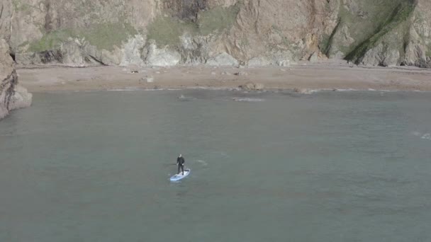 Sup Paddleboard Macho Wetsuit Partem Praia Areia Com Penhascos Íngremes — Vídeo de Stock