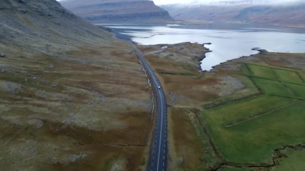 アイスランドの両側に黒い砂 緑の草 大きな湖と雪をかぶった山々と一緒に道路に沿って運転無人偵察機 — ストック動画