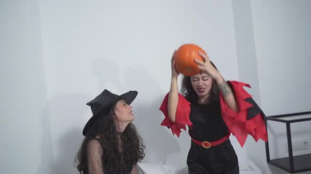 Dwie Wesołe Kobiety Czarnych Kostiumach Halloween Bawiące Się Dynią Łóżku — Wideo stockowe