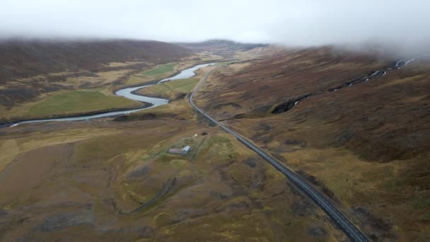 从无人驾驶飞机飞越河流和高速公路的空中俯瞰 汽车在冰岛的北极景观中穿行 两侧的山脉布满了云彩 — 图库视频影像