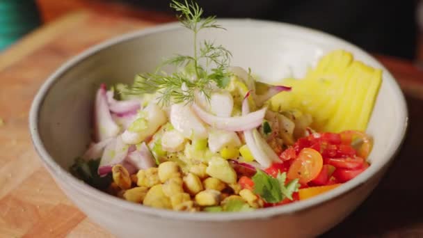 おいしいペルーのシーフードサラダ 健康的でカラフルな新鮮な準備された成分と緑豊かなフェンネルのフロントで装飾されたCevicheスターター皿の映画的なクローズアップ — ストック動画