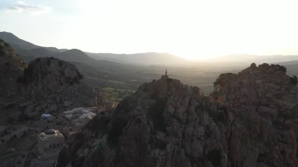 夕阳西下 一个人孤身一人站在山顶上 俯瞰着五彩斑斓的草地和小山 快速的无人机向下飞去 — 图库视频影像