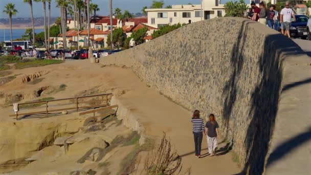 カップル歩くと 手を携えて ラホヤ カリフォルニア州の背の高い石の壁に沿って 4分の1速度に減速 — ストック動画