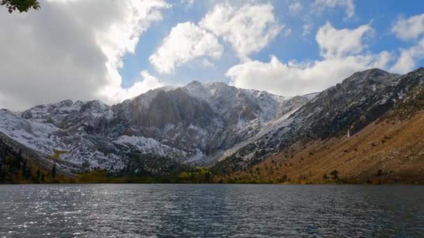 雪のシャーウィン山脈は カリフォルニア州モノで 晴れた秋の日に嵐の雲が圧延されたコニックレイク海岸線の山々 パンニングショット — ストック動画