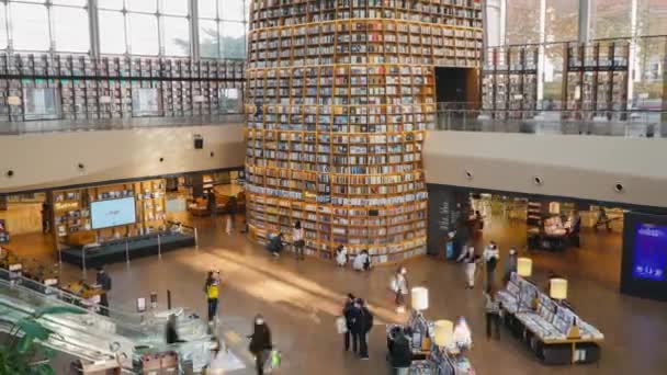 2階からのスターフィールド図書館ビュー 絵のように美しい本棚やインスタレーションで装飾された豊かなインテリアで人々が動き回る タイムラプスズームアウト — ストック動画