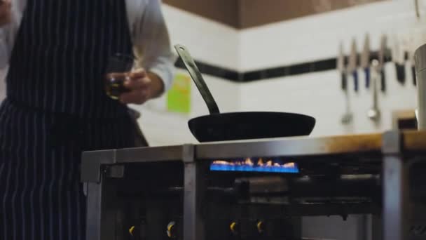 Zpomalený pohyb kuchaře vaření s ohněm v pánvi v profesionální kuchyni hodí jídlo v pánvi
