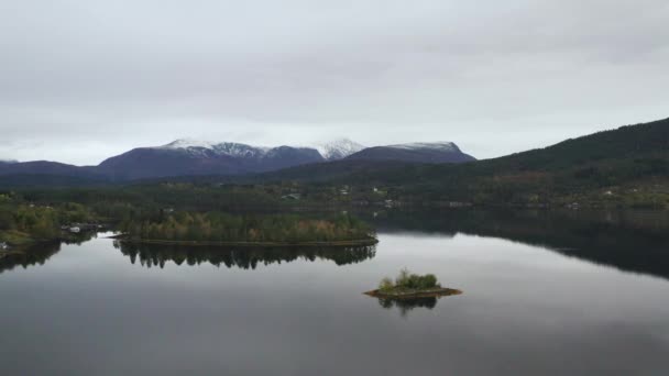ノルウェーの背景にある小さな島と山の雪景色を望む静かな湖 引き込み — ストック動画