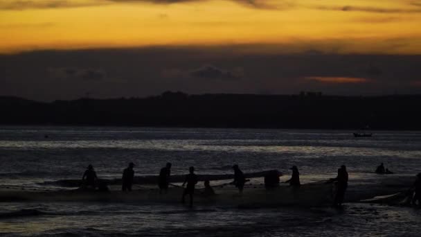 シルエット 男性のグループは ビーチの海岸に巨大な漁網を引き出す 日没時間 — ストック動画