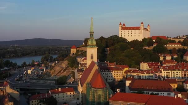 黄金の時間の間にブラチスラバのスロバキアの背景に聖マーティン大聖堂とブラチスラバ城とワイドドローンショット — ストック動画