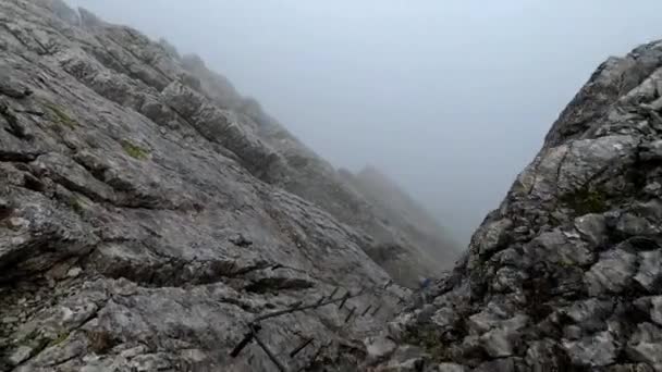 山の水平方向の岩を登るのを明らかにする かれのすぐ下には雲があり とても高い所にある — ストック動画