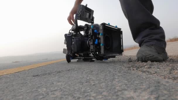 profesionální kameraman seřizující své přístroje a fotoaparát na asfaltové silnici