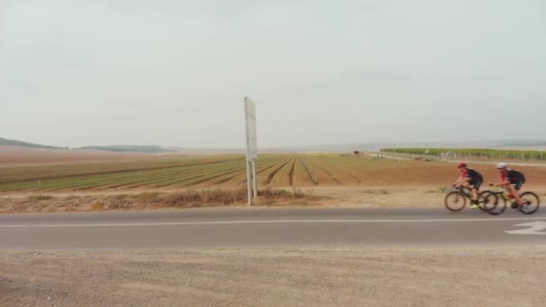 Снимок Беспилотника Два Профессиональных Велосипедиста Едут Пустынной Дороге — стоковое видео