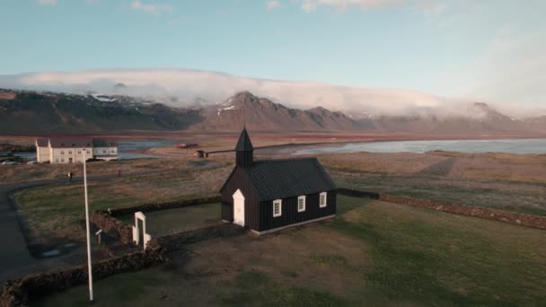アイスランドの有名な夕暮れ時のブドゥールの黒い教会からの空中撤退 — ストック動画