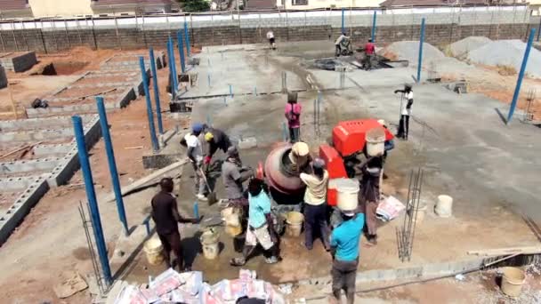 アブジャのロコゴマ地区の建物の基礎のための混合と注ぎ口セメント 頭の上にバケツを運ぶ — ストック動画