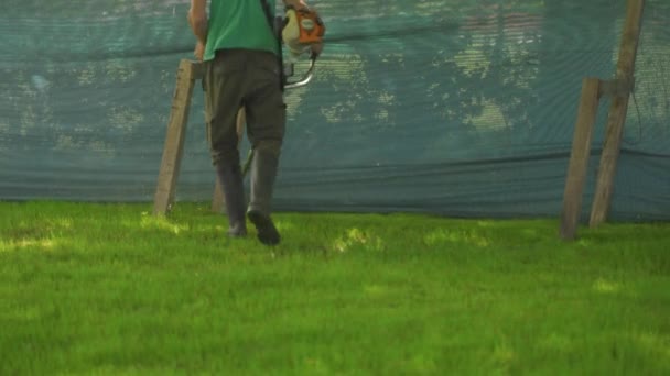 Tracking Shot Męski Pracownik Cięcia Trawy Kruszarki Ogrodzie Średni Strzał — Wideo stockowe