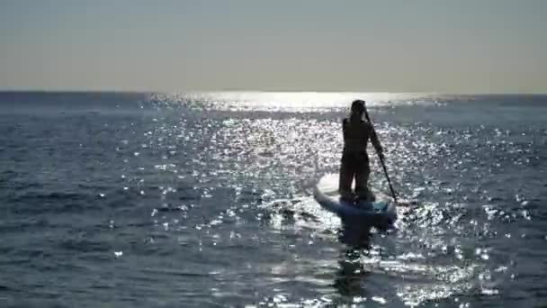 Žena Pomalu Pádluje Moře Svém Prkně Když Ranní Slunce Třpytí — Stock video