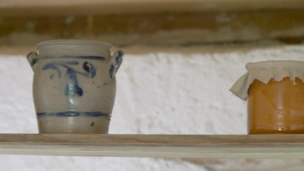 Panning záběr staré kuchyně s ročníkem džbánek a vlastní med ve skle umístěn na dřevěné desce - středověký čas 