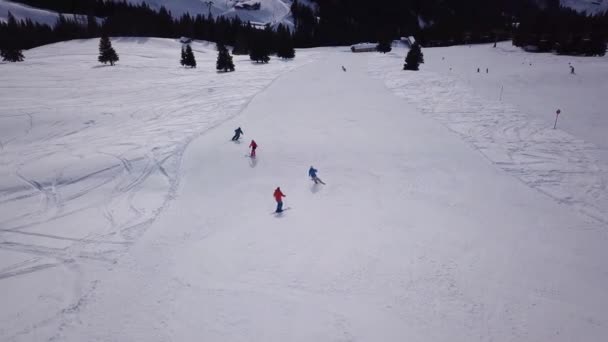 Letecký pohled na lyžařské středisko s lidmi na snowboardu z kopce. Záběry ze skladu. Létání nad lyžařskou nebo snowboardovou tratí na bílém sněhu obklopeném hustým lesem v zimním období, cestování a sportu